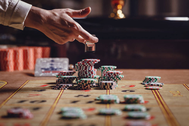 Casino, mesa de ruleta americana, el distribuidor pone Dolly en el número ganador, hay fichas en la mesa  - Foto, imagen