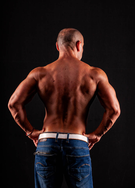 Athlete bodybuilder on a black background - Photo, image