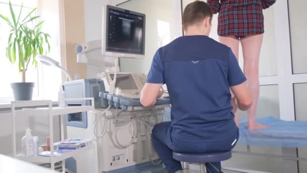 Lékař diagnostikuje žíly na nohou pomocí ultrazvukové diagnostiky. Léčba křečových žil - Záběry, video