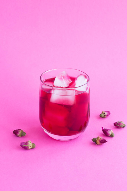 Rózsaszín koktél vagy limonádé jég és rózsa virág az ivópoharban a rózsaszín háttér. Közelkép. - Fotó, kép
