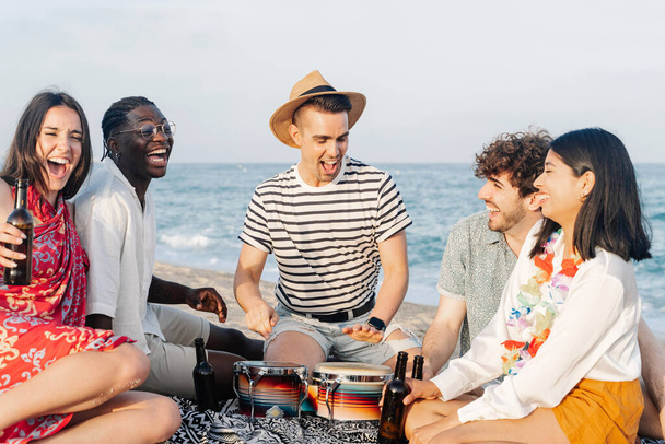 Junge Freunde haben Spaß beim Musizieren auf einer Party am Strand im Sommer - Foto, Bild
