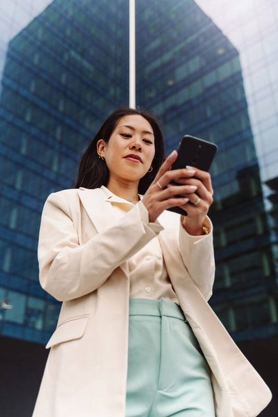 Portrait of Young Asian Elegant Professional Business Woman using cell phone to text outdoors in the city - Fotoğraf, Görsel