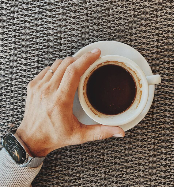 A top-view shot of a man's hand holding a cup of coffee - Foto, Bild