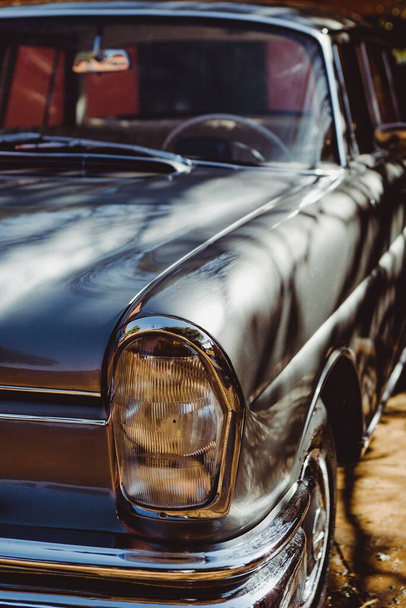 A vertical shot of a headlight of a classic old Mercedes Benz car in gray - Foto, Bild