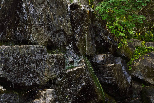 A closeup shot of wet rocks of a splashing waterfall in a forest - Foto, Imagem