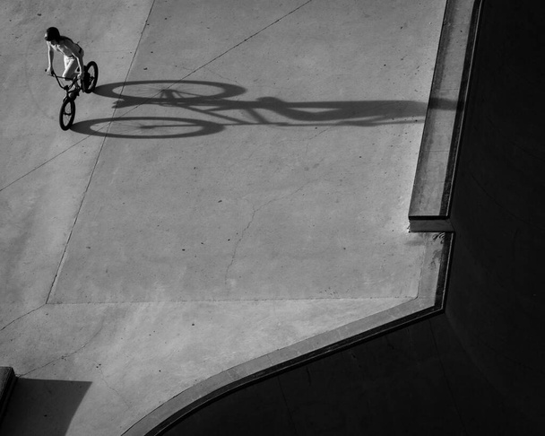 An aerial grayscale shot of TX biker at the skate park casting a long shadow - Fotografie, Obrázek