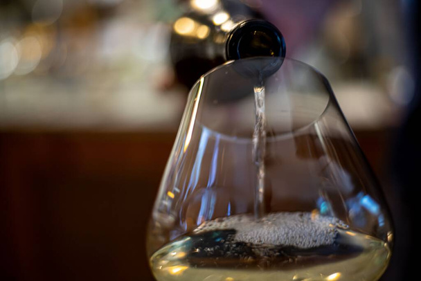 The view of a bottle feeling the glass with white wine - Fotoğraf, Görsel