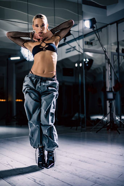A vertical view of an attractive Stiletto dancer posing before the mirror in a studio - Photo, Image