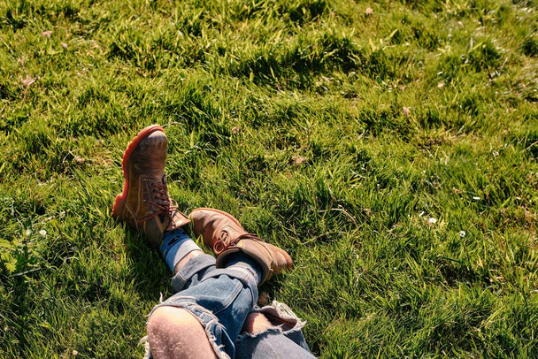 The Feet in boots of a man lying peacefully in a field of green grass with copy space - Fotografie, Obrázek