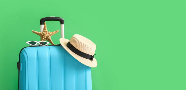 Suitcase with beach accessories on green background with space for text - Photo, Image