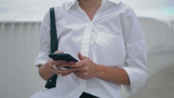 Unknown stylish business woman messaging on modern smartphone walking city street close up. Female hands holding black telephone typing on screen. Unrecognizable elegant lady texting sms on go outdoor - Φωτογραφία, εικόνα