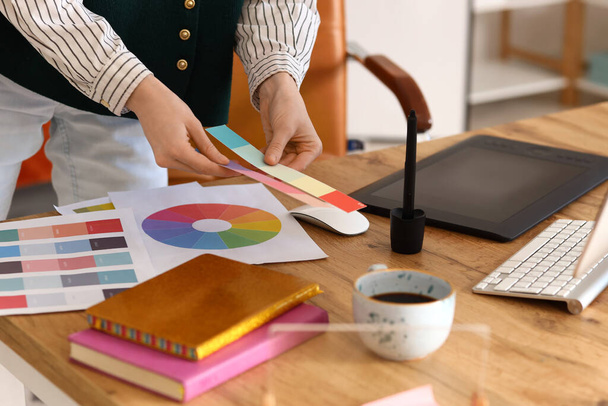Diseñadora gráfica femenina trabajando con paletas de colores en la mesa en la oficina, primer plano - Foto, imagen
