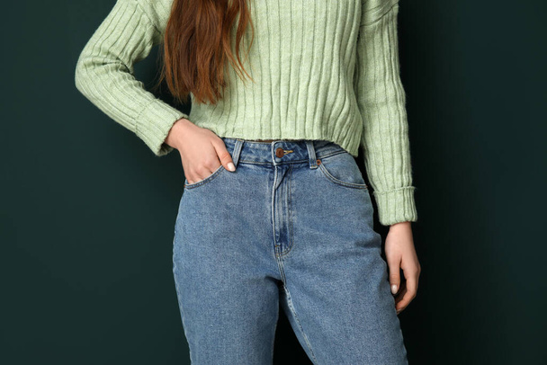 Mladá žena ve stylových džínách na zeleném pozadí, detailní záběr - Fotografie, Obrázek
