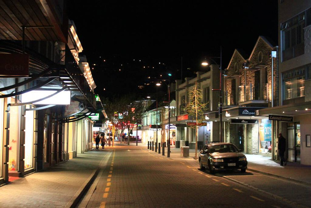 A mesmerizing night view of a street with illuminated shops in Queenstown in New Zealand - Foto, afbeelding