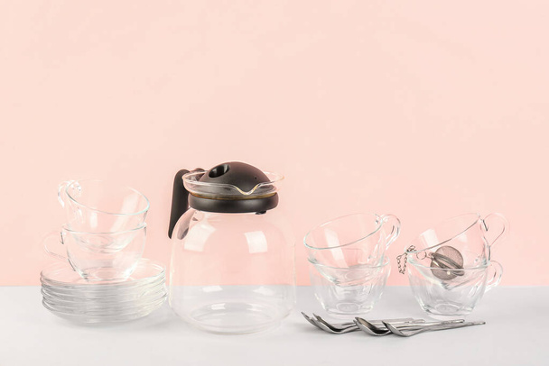 Theepot, kopjes en lepels op roze achtergrond - Foto, afbeelding