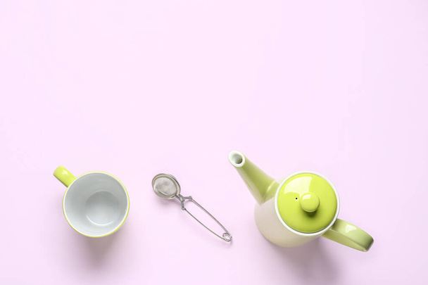 Teapot, mug and infuser on lilac background - Valokuva, kuva