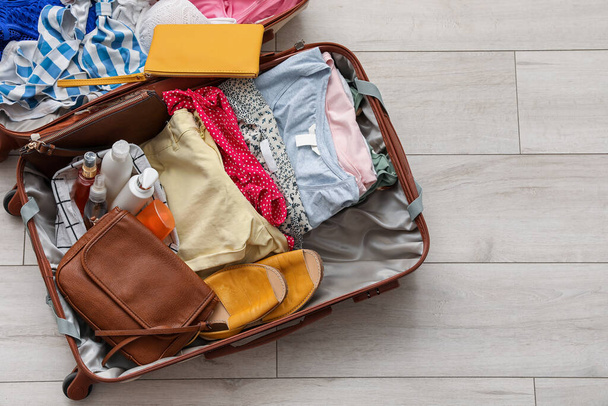 Open suitcase with clothes on light wooden floor - Photo, Image