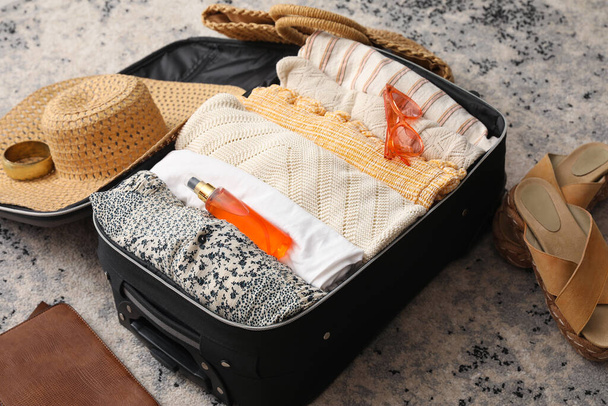 Suitcase with summer clothes and accessories on color carpet - Zdjęcie, obraz