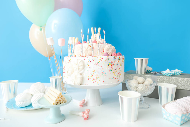 Gâteau d'anniversaire avec différents bonbons sur la table près du mur bleu - Photo, image