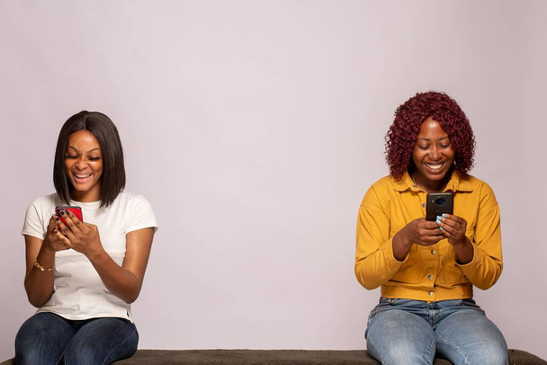 happy africans girls checking their phones - Φωτογραφία, εικόνα