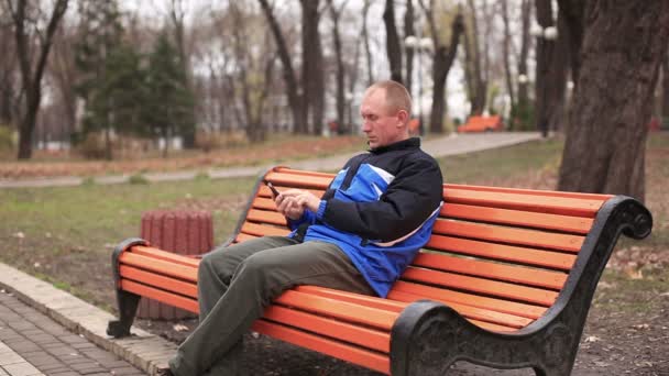 Dorosły człowiek rozmowy na telefon komórkowy w parku - Materiał filmowy, wideo