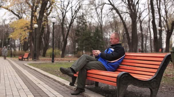 Człowiek czeka w parku - Materiał filmowy, wideo