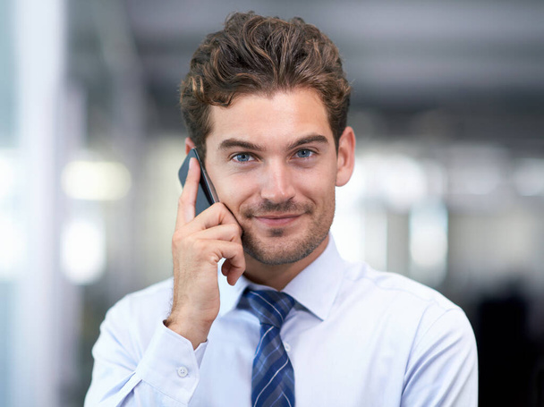 Siempre disponible para mis clientes. un joven hombre de negocios guapo hablando en su celular en el trabajo - Foto, Imagen