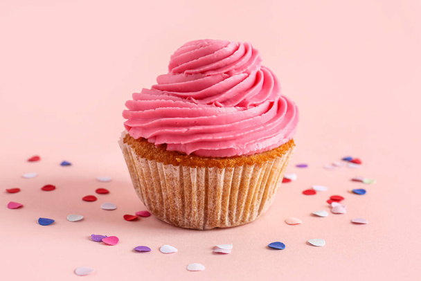 Tasty cupcake and confetti on pink background - Photo, Image