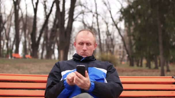 Homme sérieux adulte parlant sur mobile dans le parc. Vue de face
 - Séquence, vidéo