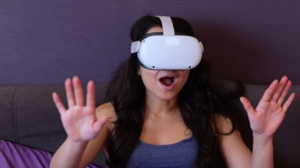 Gelukkig vrouwtje dat virtual reality gebruikt voor simulatie 3D. Vrouw met een virtual reality bril om thuis te spelen. Modern technologie concept. Langzame beweging - Video