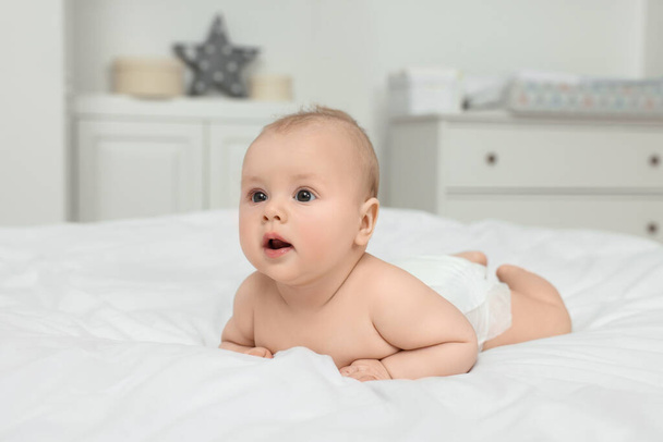 Cute baby lying on white bed at home - Foto, afbeelding