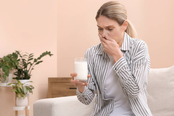 Nainen, jolla on lasillinen maitoa, joka kärsii laktoosi-intoleranssista kotona, tilaa tekstille - Valokuva, kuva