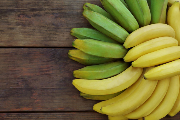 Bunches of tasty bananas on wooden table, flat lay. Space for text - Foto, Bild