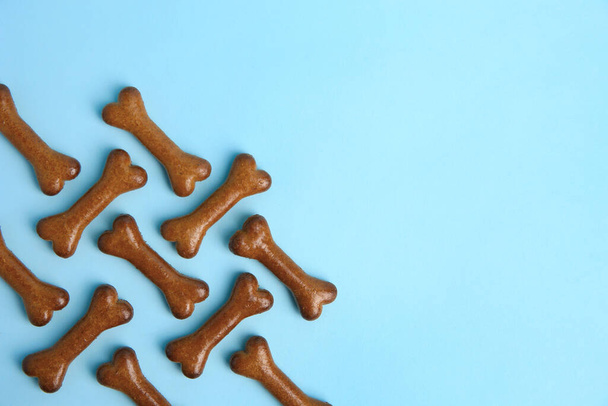 Bone shaped dog cookies on light blue background, flat lay. Space for text - Zdjęcie, obraz