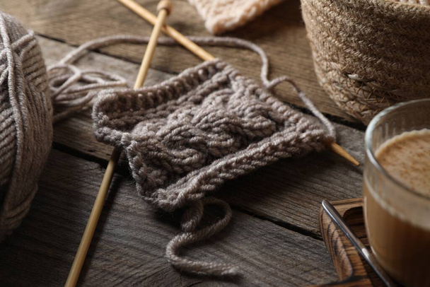 Grey knitting and needles on wooden table, closeup - Fotoğraf, Görsel