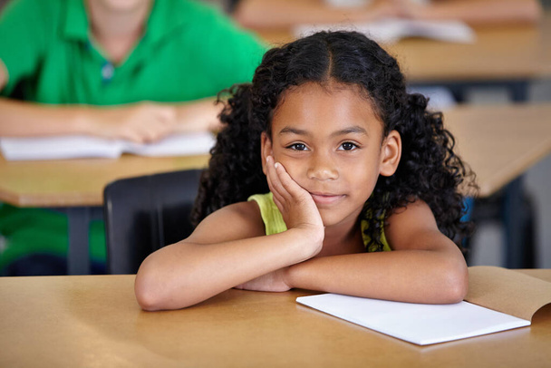 Schule ist immer interessant. Ein gelangweilt aussehendes ethnisches Mädchen sitzt an ihrem Schreibtisch in der Schule - Foto, Bild