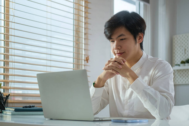 Hezký mladý podnikatel v bílé košili čtení e-mail na notebooku. - Fotografie, Obrázek