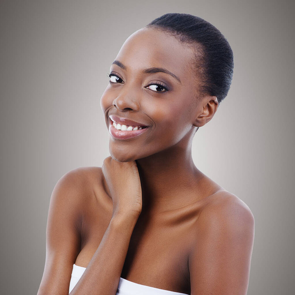 Haar glimlach verlicht de kamer. Portret van een mooie Afrikaanse vrouw die haar huid aanraakt - Foto, afbeelding