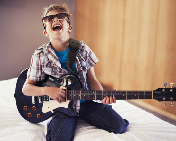 Youre never too young to learn a Slayer riff. A little boy playing an electric guitar in his bedroom - Foto, afbeelding