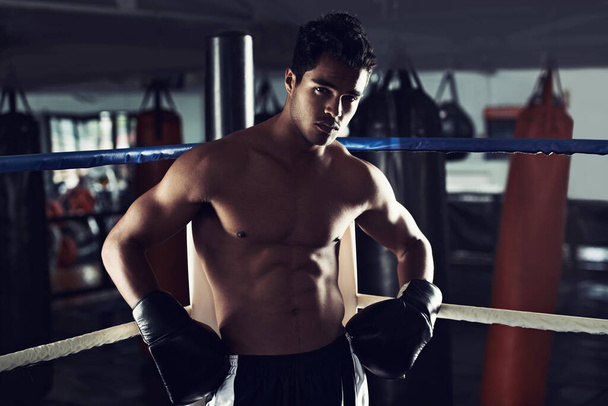 彼はボクシングのスポーツに専念している。ボクシングリングの角に立つ若い男性ボクサーの肖像画 - 写真・画像