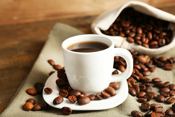 Cup of coffee with beans on rustic wooden background - Foto, imagen