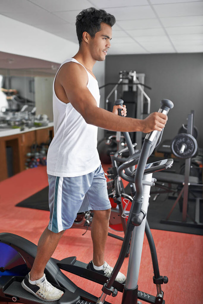 Hes always in the gym. A young ethnic man exercising in the gym - Zdjęcie, obraz