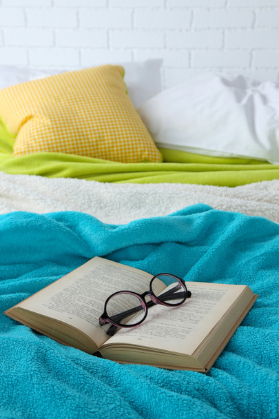 Book and glasses on bed close-up - Foto, afbeelding