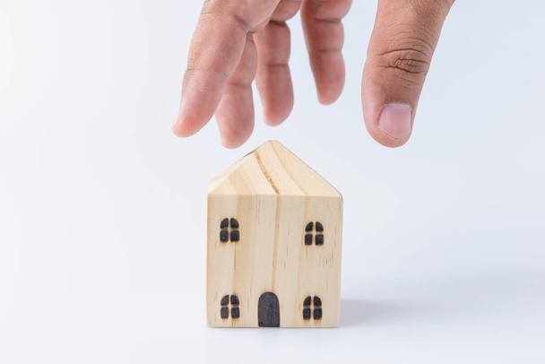 Un homme de main ramasse une petite maison en bois sur fond blanc avec espace de copie. Les concepts d'investissement immobilier, la finance, la banque et l'épargne. Entreprise de résidence peut faire un profit à l'avenir. - Photo, image