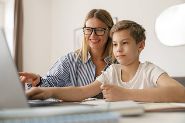 Happy mom and son doing homework and studying with laptop together. High quality photo - Zdjęcie, obraz