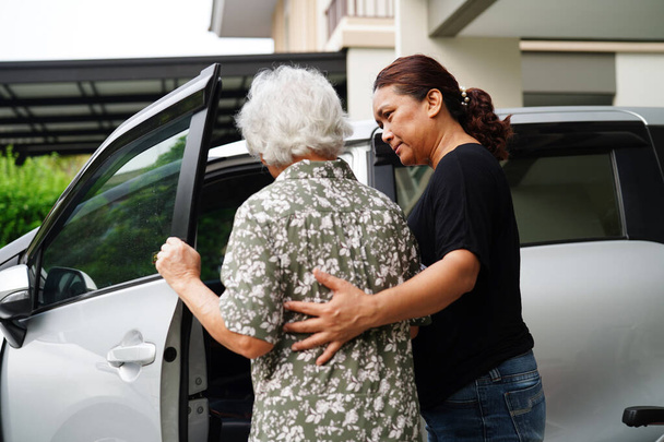 Caregiver help Asian elderly woman disability patient get in her car, medical concept. - Valokuva, kuva