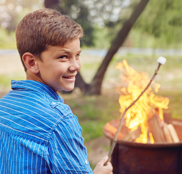 De beste kampvuurtraktatie. een jongen roosteren marshmallows tijdens het kamperen samen - Foto, afbeelding