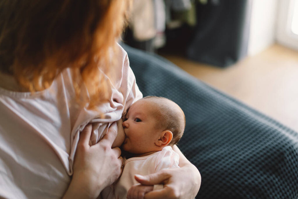 Newborn baby girl sucking milk from mothers breast. Portrait of mom and breastfeeding baby. Concept of healthy and natural baby breastfeeding nutrition. - Foto, Bild