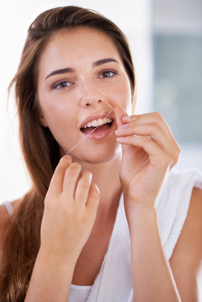 She knows the importance of flossing. Portrait of an attractive young woman holding dental floss and smiling - Photo, image