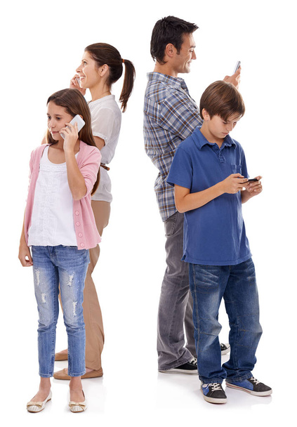 Together but separated. Studio shot of four family members each using their own mobile phones - Photo, image
